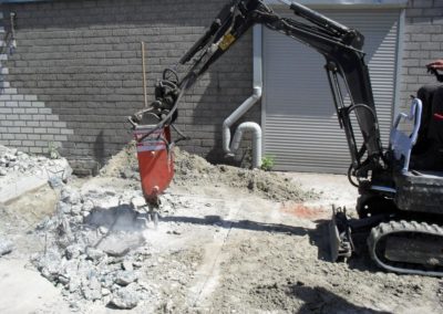 mini kraan sloopt beton vloer met hydraulische hamer