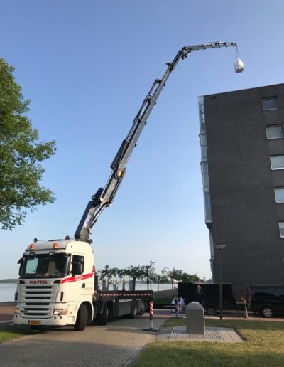 Autolaadkraan uitgeschoven boven gebouw